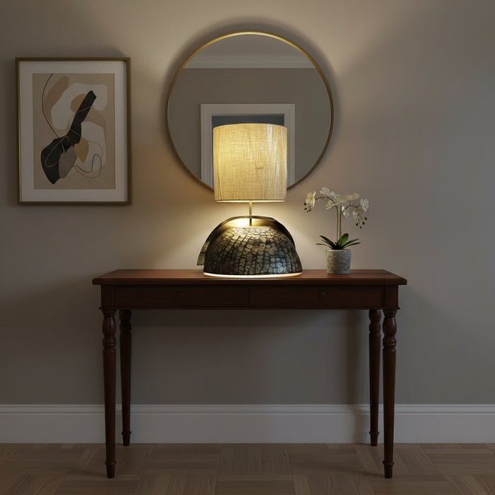 Table lamp with textured base and beige shade on a dark surface.