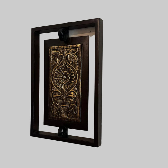 Decorative wall art with floral design in a black frame on a textured white wall.