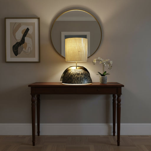 Table lamp with textured base and beige shade on a dark surface.