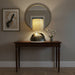 Table lamp with textured base and beige shade on a dark surface.