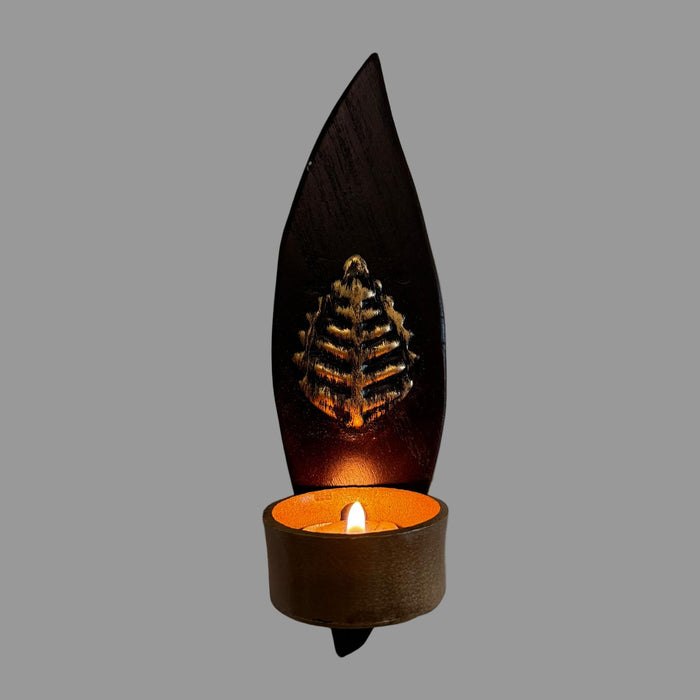 Wax candle holder shaped like a leaf on a textured wall